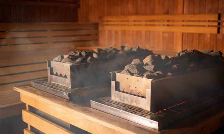 Heater in sauna with hot stones among steam